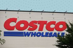 a costco store sign on the side of a building with birds perched on it