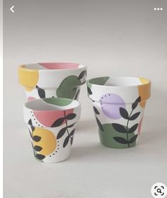 four cups with different designs on them sitting next to each other in front of a white background