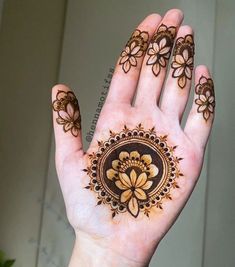 a woman's hand with henna tattoos on it and flowers painted on the palm