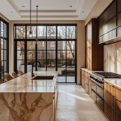 a kitchen with marble counter tops and an island in front of large windows that look out onto the yard