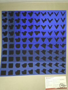 an art piece is displayed in front of a blue background with black shapes on it