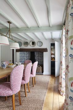 a dining room table with pink chairs next to a fireplace