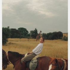 a woman riding on the back of a brown and white horse in an open field