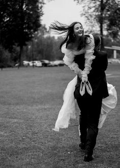 black and white photograph of a bride carrying her groom on his back in the park