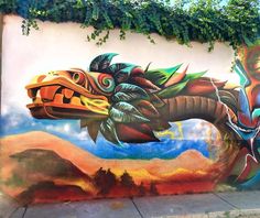 a large mural on the side of a building with a dragon painted on it's face