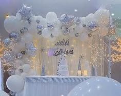 a table with white balloons and silver decorations