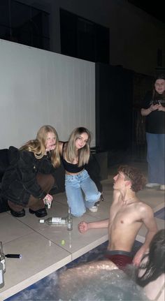 three young people are sitting in the water and one man is taking a bath with his friend