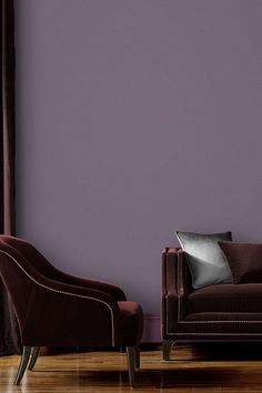 a living room with two chairs and a couch in front of a purple painted wall