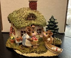 a figurine of two mice sitting in front of a house with grass roof