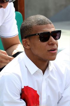 a man wearing sunglasses and a white shirt with a red flower on the collared shirt