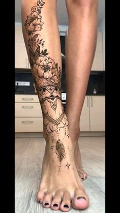 a woman's legs with tattoos on them and flowers in the middle of her leg