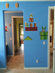 a blue room with mario bros wall decals on the walls, and an open door leading to another room