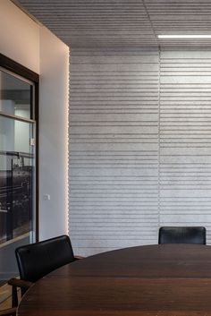 an empty conference room with black leather chairs and a wooden table in front of a white wall