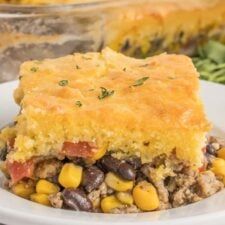 a close up of a plate of food with corn and beans on it, next to a casserole dish