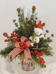 a white teddy bear sitting on top of a christmas tree in a tin with red berries and pine cones