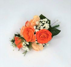 an arrangement of orange roses and baby's breath on a white background with greenery