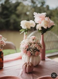 two vases filled with flowers sitting on top of a pink table cloth covered table