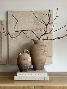 two vases sitting on top of a wooden table in front of a wall painting