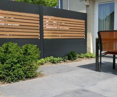 an outdoor table and chairs in front of a fenced in area with plants on the side