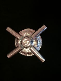 a glass plate with three metal blades sticking out of it's center, on a black background