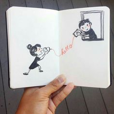 a person holding an open book with drawings on it