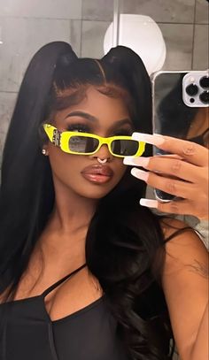 a woman taking a selfie in front of a mirror with yellow sunglasses on her face