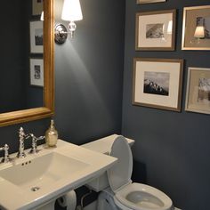 a white toilet sitting under a bathroom mirror next to a sink with faucet