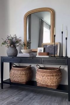 a console table with two baskets and a mirror