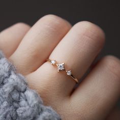 a woman's hand wearing a gold ring with three small diamonds on the band