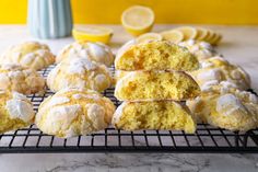 a bunch of lemon muffins sitting on a cooling rack with powdered sugar