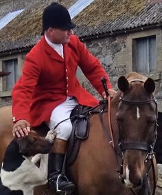 a man riding on the back of a brown horse next to a black and white dog