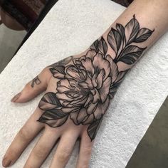 a woman's hand with a flower tattoo on it