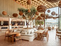 a restaurant with tables, chairs and hanging baskets on the ceiling over looking the water