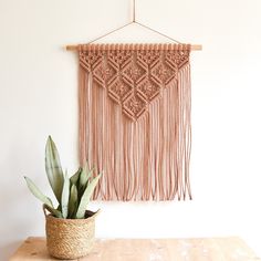 a potted plant sitting on top of a wooden table next to a wall hanging