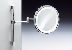 a close up of a mirror on a wall with a light attached to the side