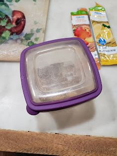 there is a purple container on the table next to other food items and some bags