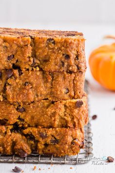 a stack of pumpkin chocolate chip bread on a cooling rack next to an orange pumpkin