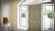 a white door with an arched glass window above it and a vase filled with flowers on the side