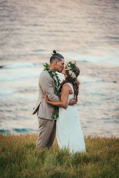 a bride and groom kissing in front of the ocean at their beach wedding ceremony on oahulua