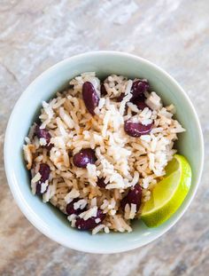 a bowl filled with rice and beans next to a lime wedge on top of a table