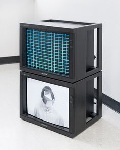 two black cubes with blue squares on the front and one has a man's face on it