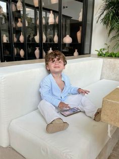 a young boy sitting on top of a white couch