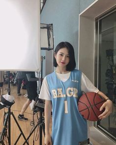 a woman holding a basketball standing in front of a camera