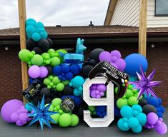 balloons and streamers in the shape of numbers are displayed on a driveway for an outdoor birthday party