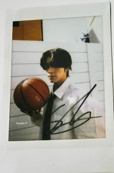 an autographed photo of a young man holding a basketball and wearing a tie