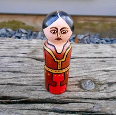 a small wooden doll sitting on top of a piece of wood