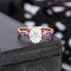 a close up of a ring on top of a wooden table with white and purple stones