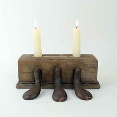 three candles are placed on top of two wooden legs with one candle in the middle