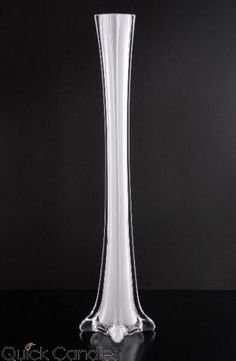 a tall clear glass vase sitting on top of a black table next to a wall