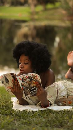 a woman laying on the grass reading a book